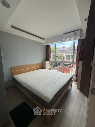 Modern bedroom with large window and natural light, featuring a minimalist design and air conditioning.