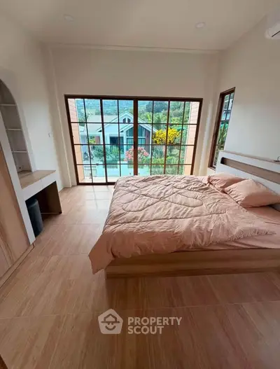 Spacious bedroom with large windows offering scenic views, featuring a cozy bed and modern decor.