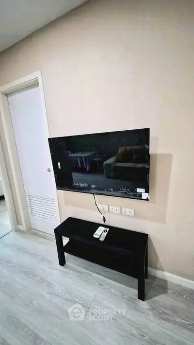 Modern living room with wall-mounted TV and sleek black console table.