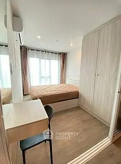 Cozy bedroom with wooden flooring, built-in wardrobe, and a study desk near a large window.