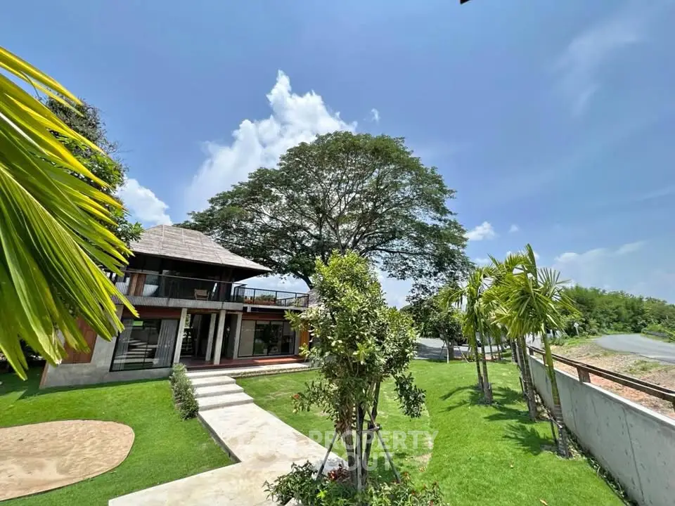 Stunning modern home with lush garden and spacious balcony under a clear blue sky.