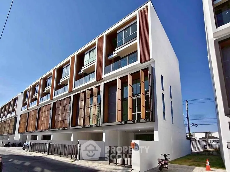 Modern townhouse exterior with sleek design and large windows in a sunny neighborhood.