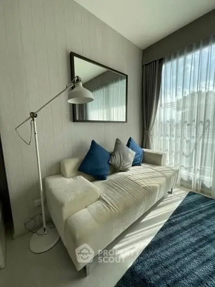 Modern living room with stylish sofa, floor lamp, and large window for natural light.