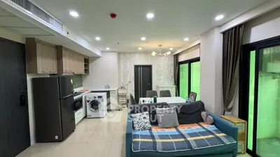 Modern open-plan living room with kitchen, featuring cozy sofa and washing machine.