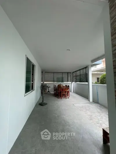 Spacious covered outdoor area with dining set and fan, perfect for entertaining.