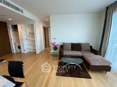 Modern living room with hardwood floors, cozy sectional sofa, and natural light from large windows.