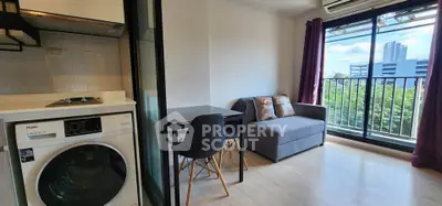 Modern apartment with balcony view, featuring compact living area and in-unit washer.