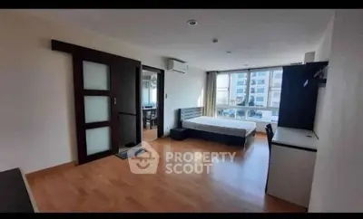 Spacious bedroom with wooden flooring and large window view