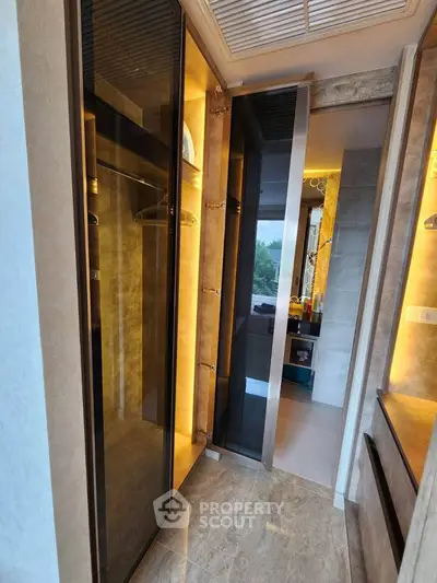 Luxurious modern closet with sleek glass doors and ambient lighting in a stylish apartment.