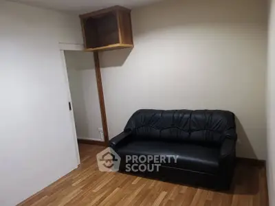 Cozy small living room with black leather sofa and wooden flooring