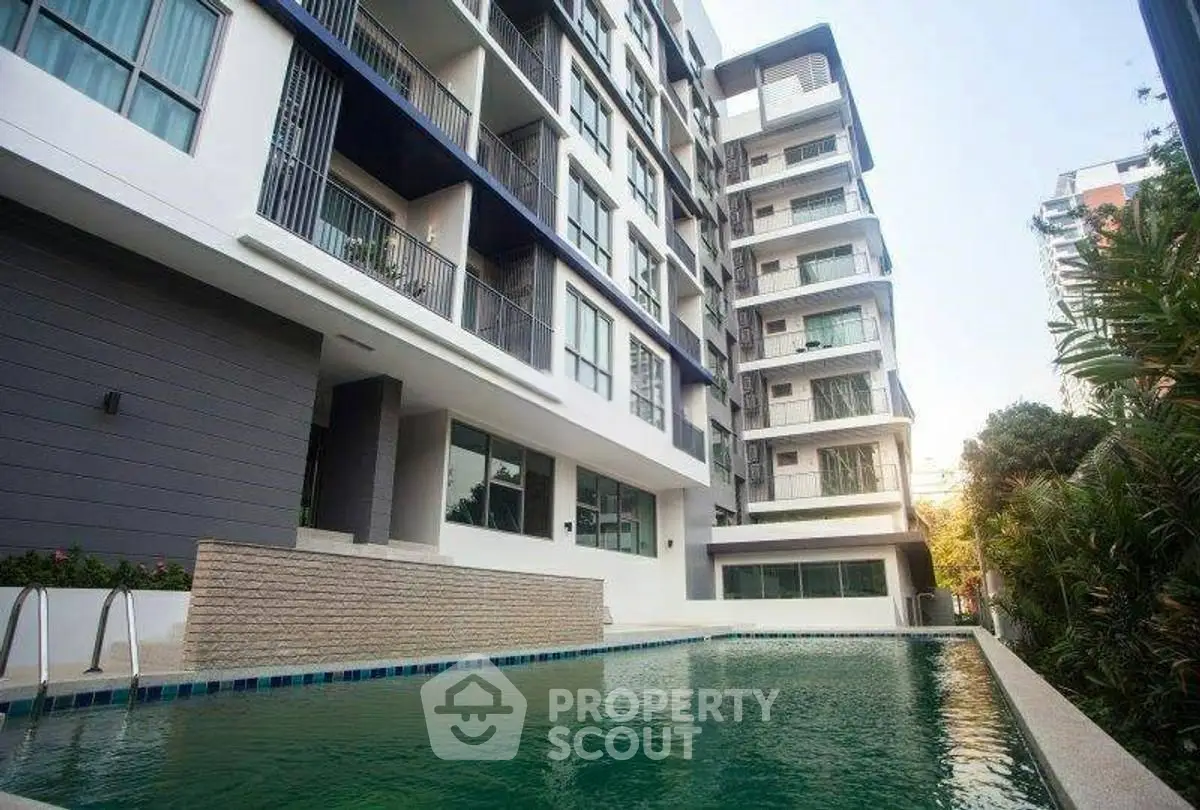 Modern apartment building with pool and lush greenery, perfect for urban living.