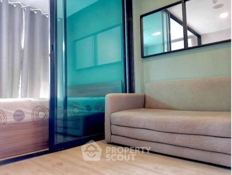 Modern apartment interior with cozy living room and adjacent bedroom separated by glass partition.