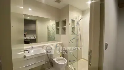 Modern bathroom with glass shower and large mirror in contemporary apartment.