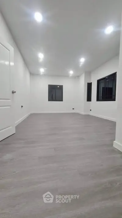 Spacious modern living room with sleek flooring and recessed lighting, perfect for contemporary living.