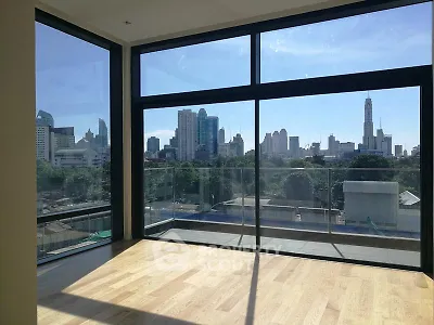 Spacious modern living room with floor-to-ceiling windows offering stunning city skyline views.
