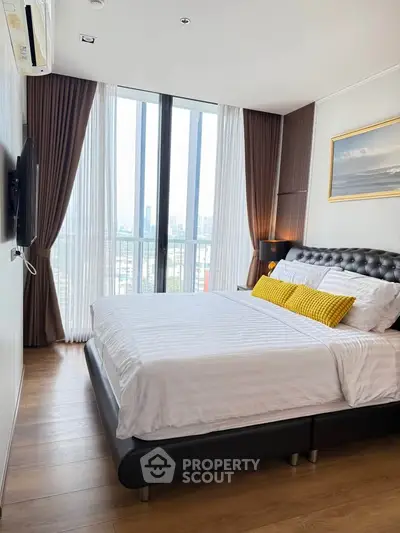 Modern bedroom with city view, featuring elegant decor and floor-to-ceiling windows.