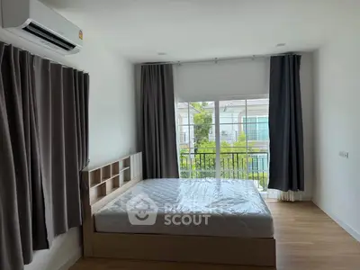 Spacious bedroom with large window and balcony view in modern apartment