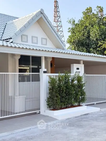 Charming single-story home with white picket fence and lush greenery, perfect for modern family living.