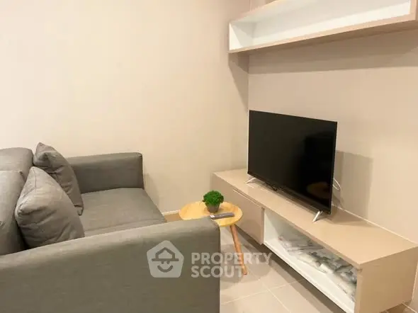Modern living room with sleek gray sofa and flat-screen TV on stylish stand.