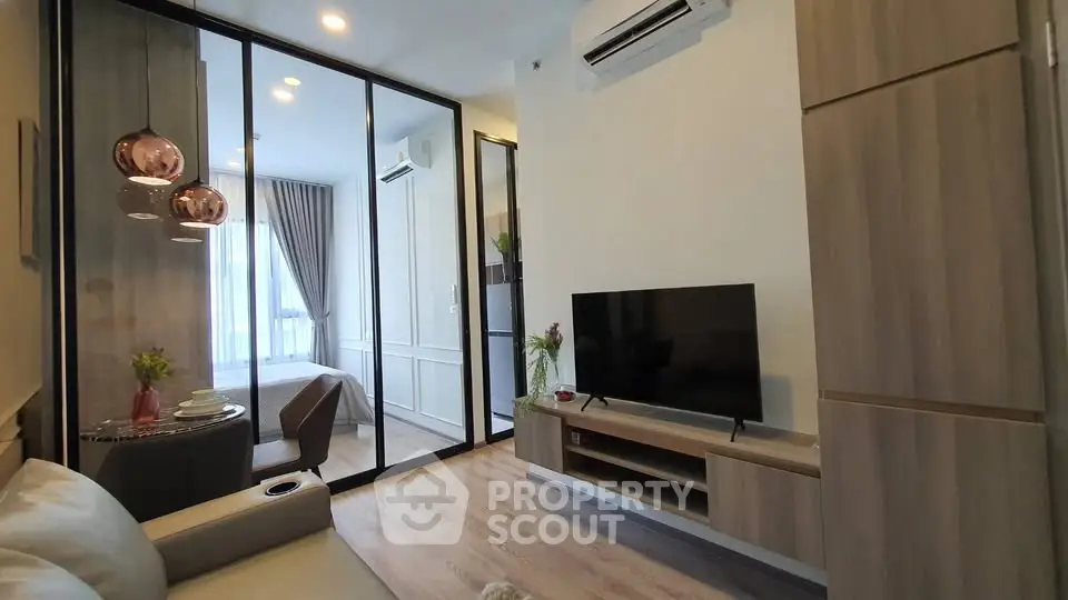 Modern living room with glass partition, cozy seating, and sleek TV setup in stylish apartment.