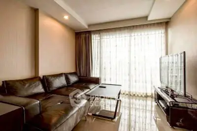 Modern living room with sleek leather sofa and large TV, featuring floor-to-ceiling windows for natural light.