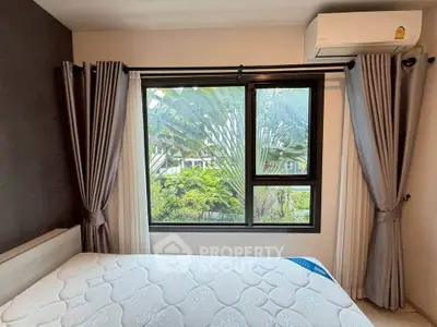 Cozy bedroom with large window and lush garden view, featuring modern air conditioning and elegant curtains.