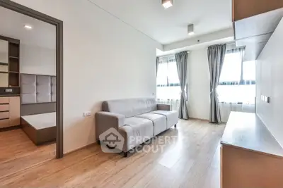 Modern living room with wooden flooring and natural light, featuring a cozy gray sofa and elegant curtains.