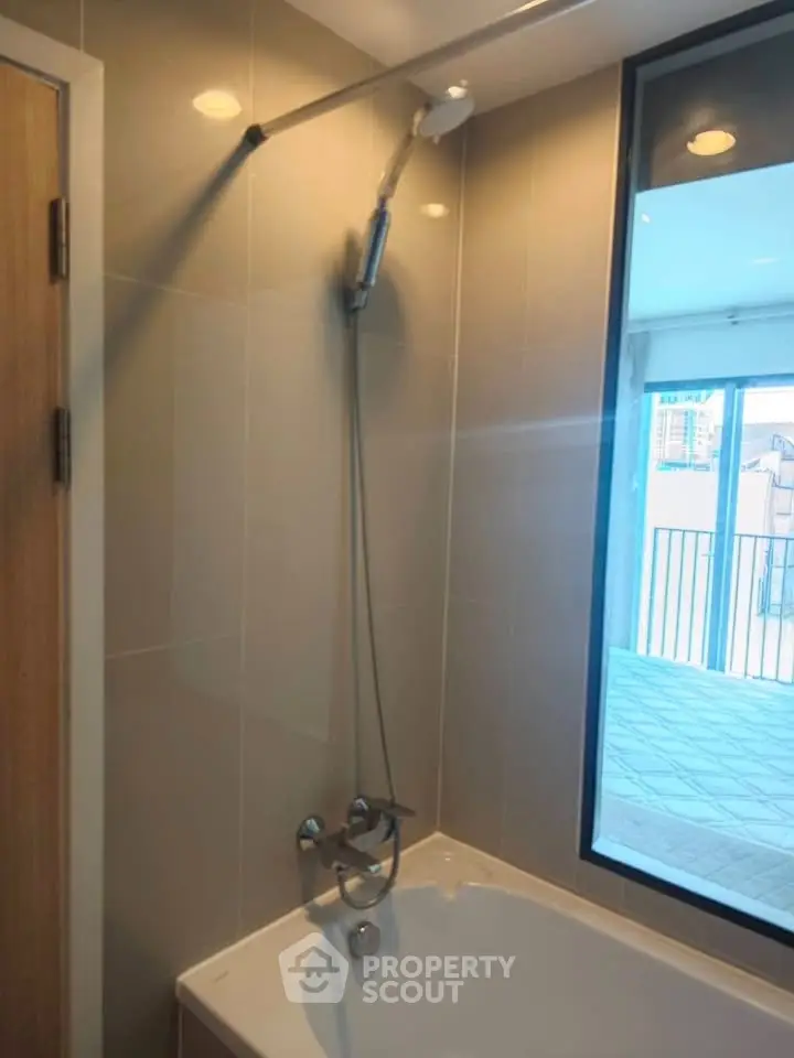 Modern bathroom with bathtub and large window offering natural light and city view.