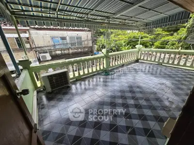 Spacious tiled balcony with awning and lush green view, perfect for outdoor relaxation.
