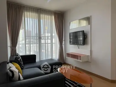 Modern living room with sleek black sofa and wall-mounted TV, featuring large windows and stylish decor.
