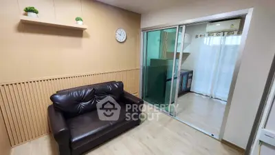 Modern living room with sleek leather sofa and sliding glass doors leading to a stylish kitchen.
