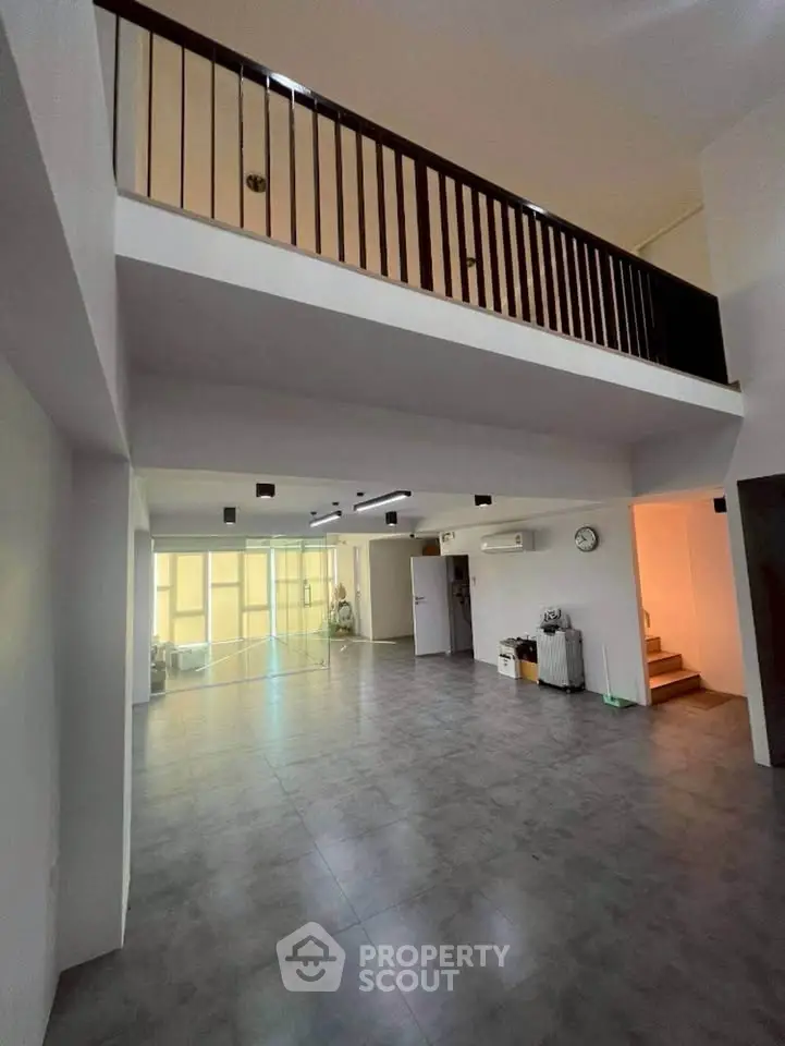 Spacious modern living room with high ceiling and mezzanine, featuring sleek design and ample natural light.