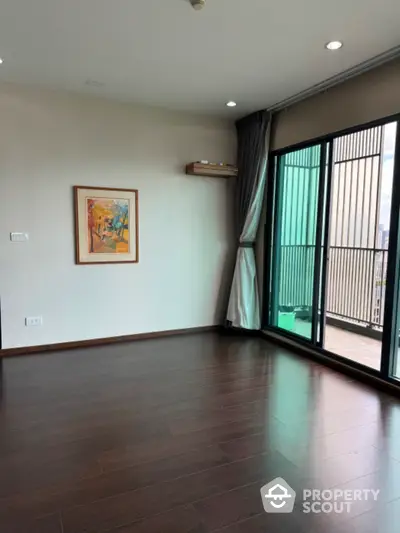 Spacious living room with wooden flooring and balcony access in modern apartment