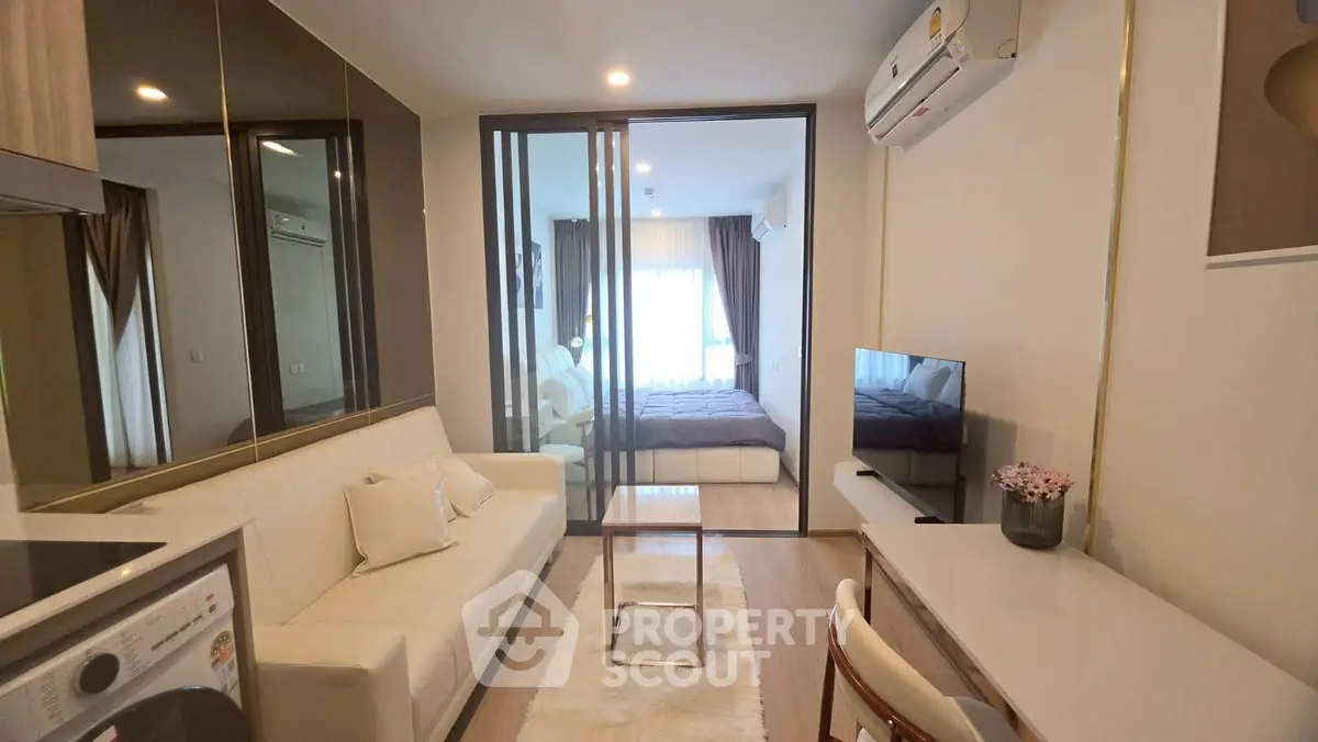 Modern studio apartment with glass partition, cozy living area, and sleek furnishings.