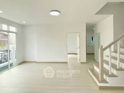 Spacious modern living room with staircase and large windows for natural light.