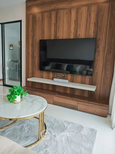 Modern living room with stylish wood paneling and mounted TV, featuring a chic marble coffee table.