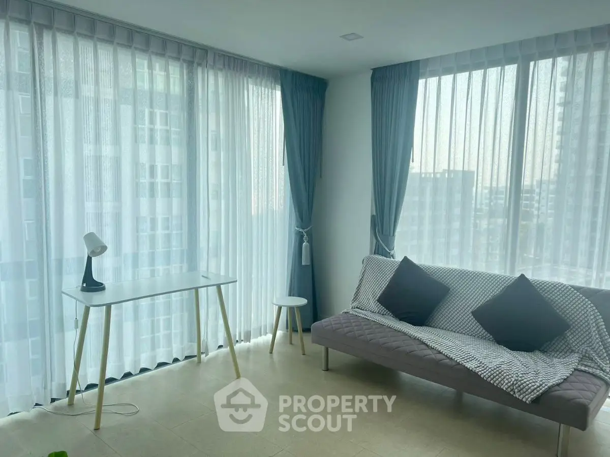 Modern living room with large windows and stylish furniture in a high-rise apartment.