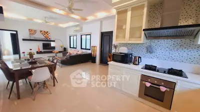 Spacious open-plan living room and kitchen with modern decor and ample natural light.