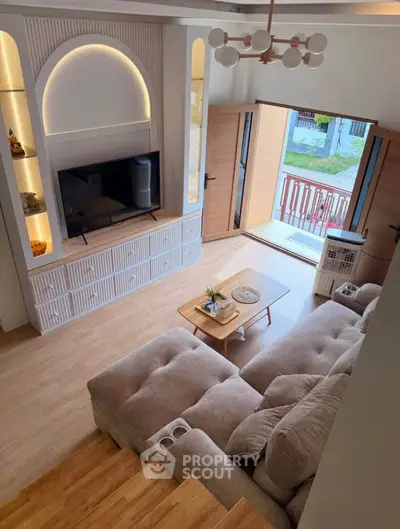 Stylish living room with cozy sectional sofa, modern TV unit, and balcony access in a bright, inviting space.