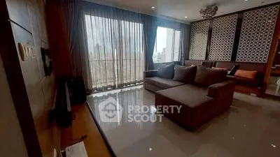 Spacious living room with large windows and modern decor in a high-rise apartment.