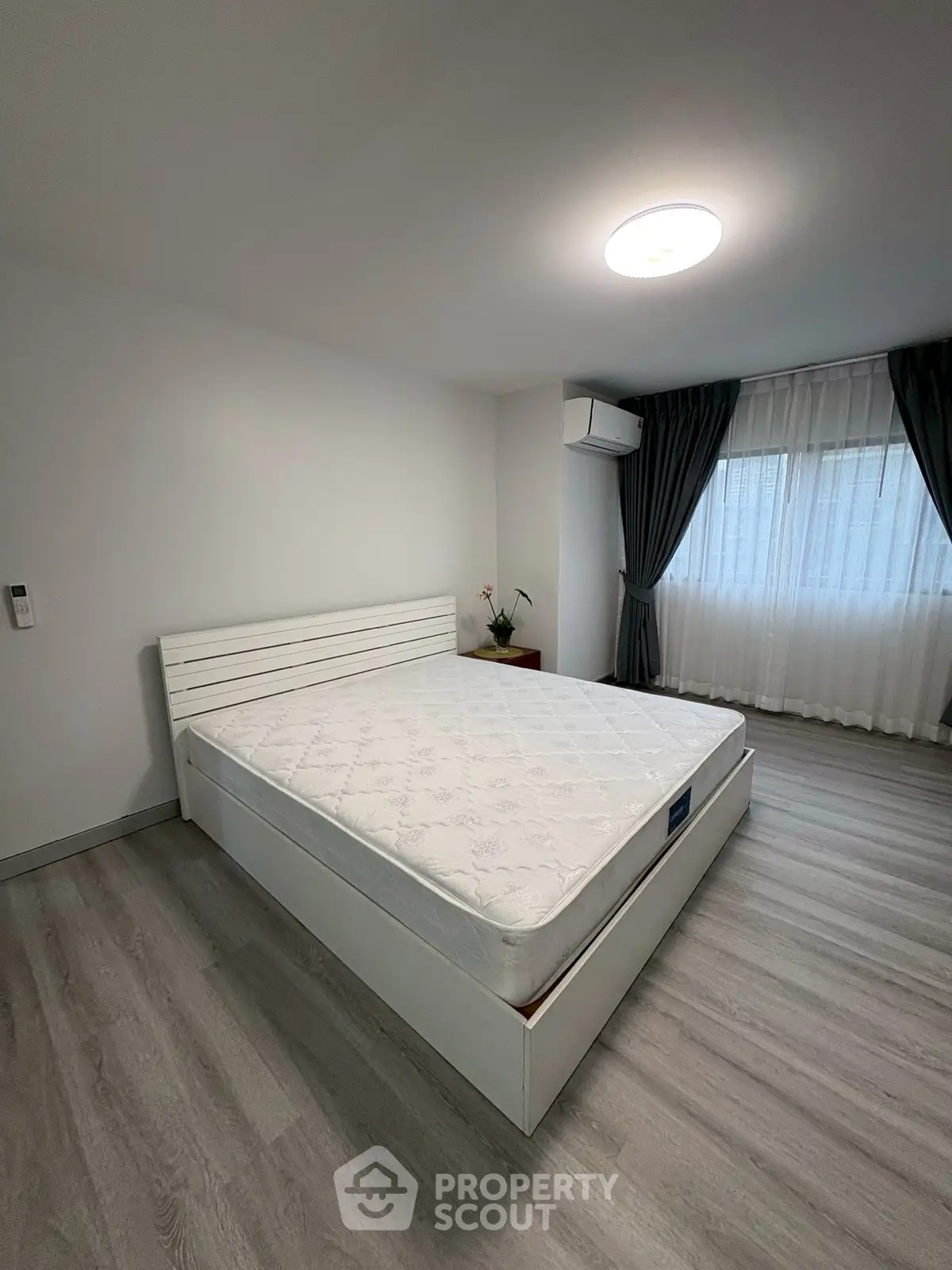 Spacious bedroom with modern decor and large window for natural light