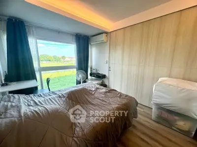 Cozy bedroom with large window and built-in wardrobe, featuring serene outdoor view.