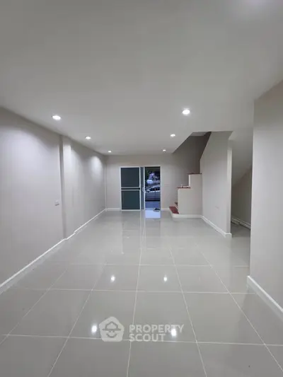 Spacious modern interior with sleek tiled flooring and minimalist design, perfect for versatile living space.