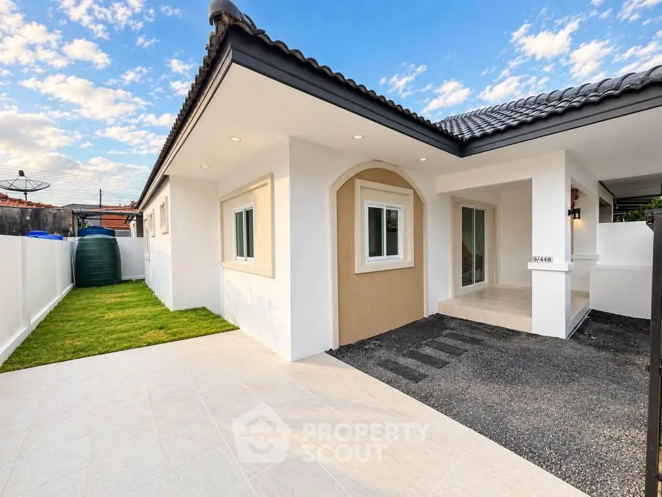 Modern single-story home with spacious driveway and manicured lawn under a clear blue sky.