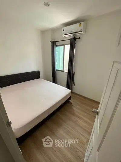 Cozy bedroom with wooden flooring and air conditioning in modern apartment.