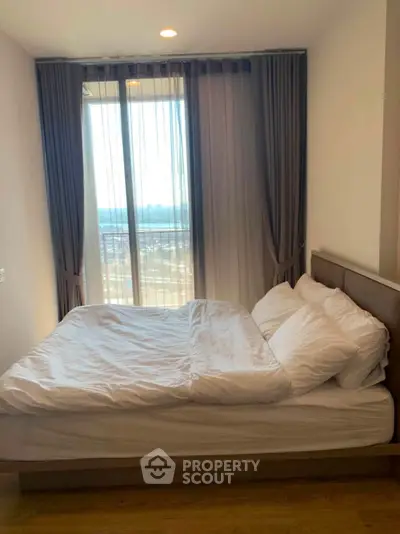Cozy bedroom with large window and elegant curtains, offering a serene and inviting atmosphere.