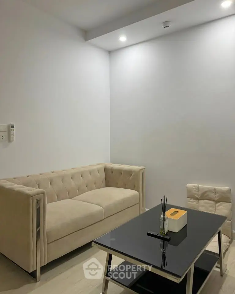 Modern living room with beige sofa and sleek black coffee table in minimalist design.