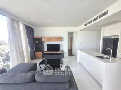 Modern living room with city view, featuring sleek furniture and open kitchen layout.