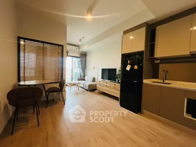 Modern open-layout living room with kitchen, featuring stylish furniture and natural light.