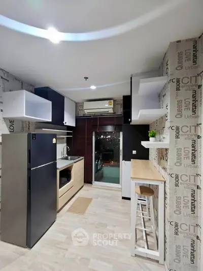 Modern kitchen with sleek appliances and stylish decor, featuring a breakfast bar and city-themed wallpaper.